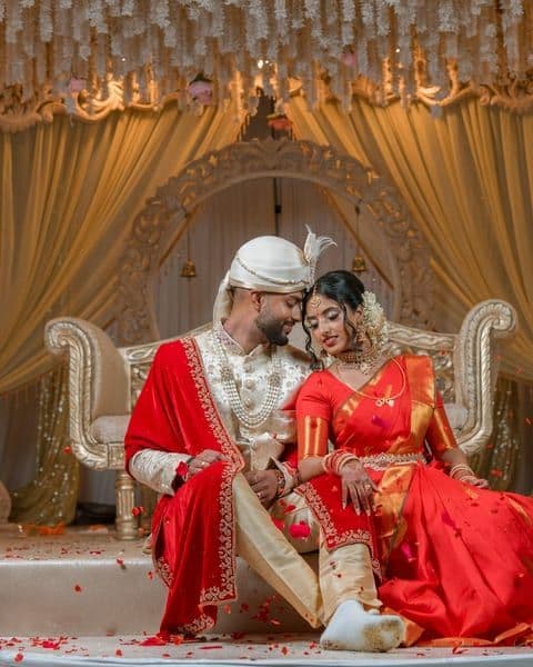 A bride in a pink lehenga and gold jewellery, looking to camera