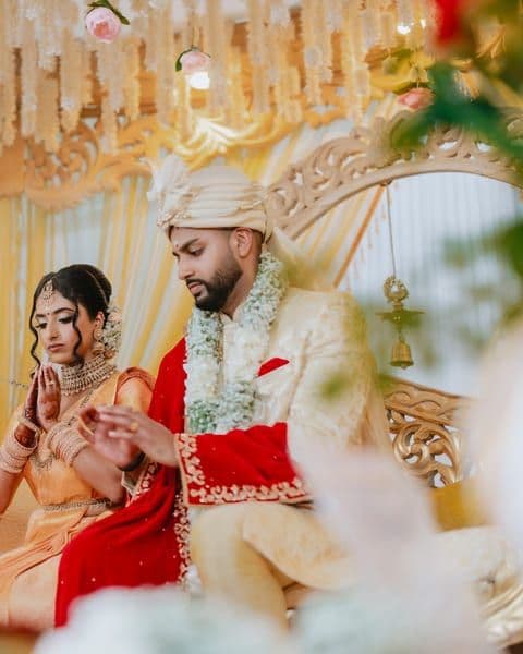 A bride in a red veil with her hands folded