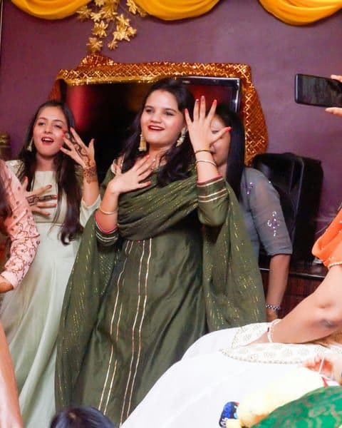 Three women in saris smiling together at a celebration