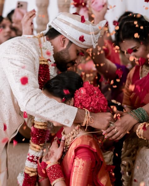 Couple showered with flower petals during traditional indian wedding ceremony