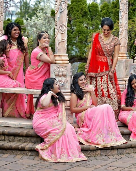 Women in red and gold saris seated together on a bench
