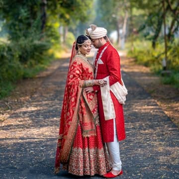 A bride and groom standing on a path in the woods
